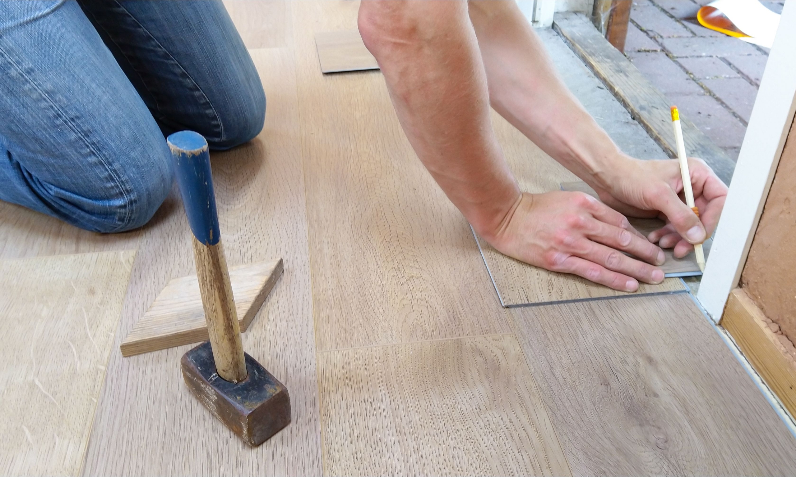 A craftsperson carefully measures and marks wooden floor panels for precise installation.