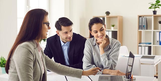 a-businesswoman-presenting-information-on-a-laptop-to-a-smiling-couple-in-an-office a-businesswoman-presenting-information-on-a-laptop-to-a-smiling-couple-in-an-office