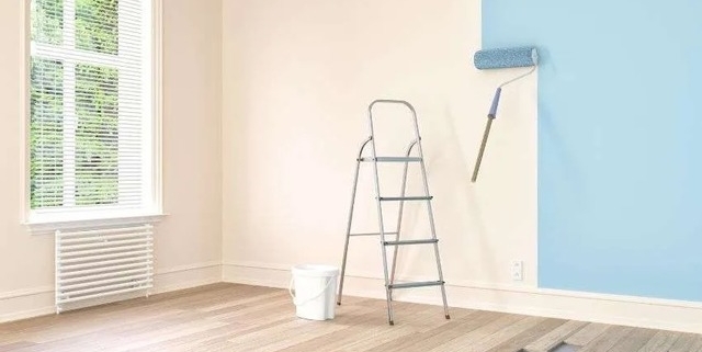 a-lander-and-paint-roller-in-a-white-room-with-the-roller-painting-the-walls-blue