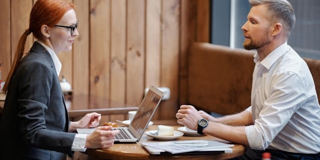 a-man-and-a-woman-having-a-business-discussion-at-a-caf-table-with-a-laptop-and-documents a-man-and-a-woman-having-a-business-discussion-at-a-caf-table-with-a-laptop-and-documents
