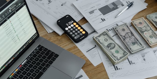 cluttered-desk-with-documents-laptop-calculator-app-and-cash