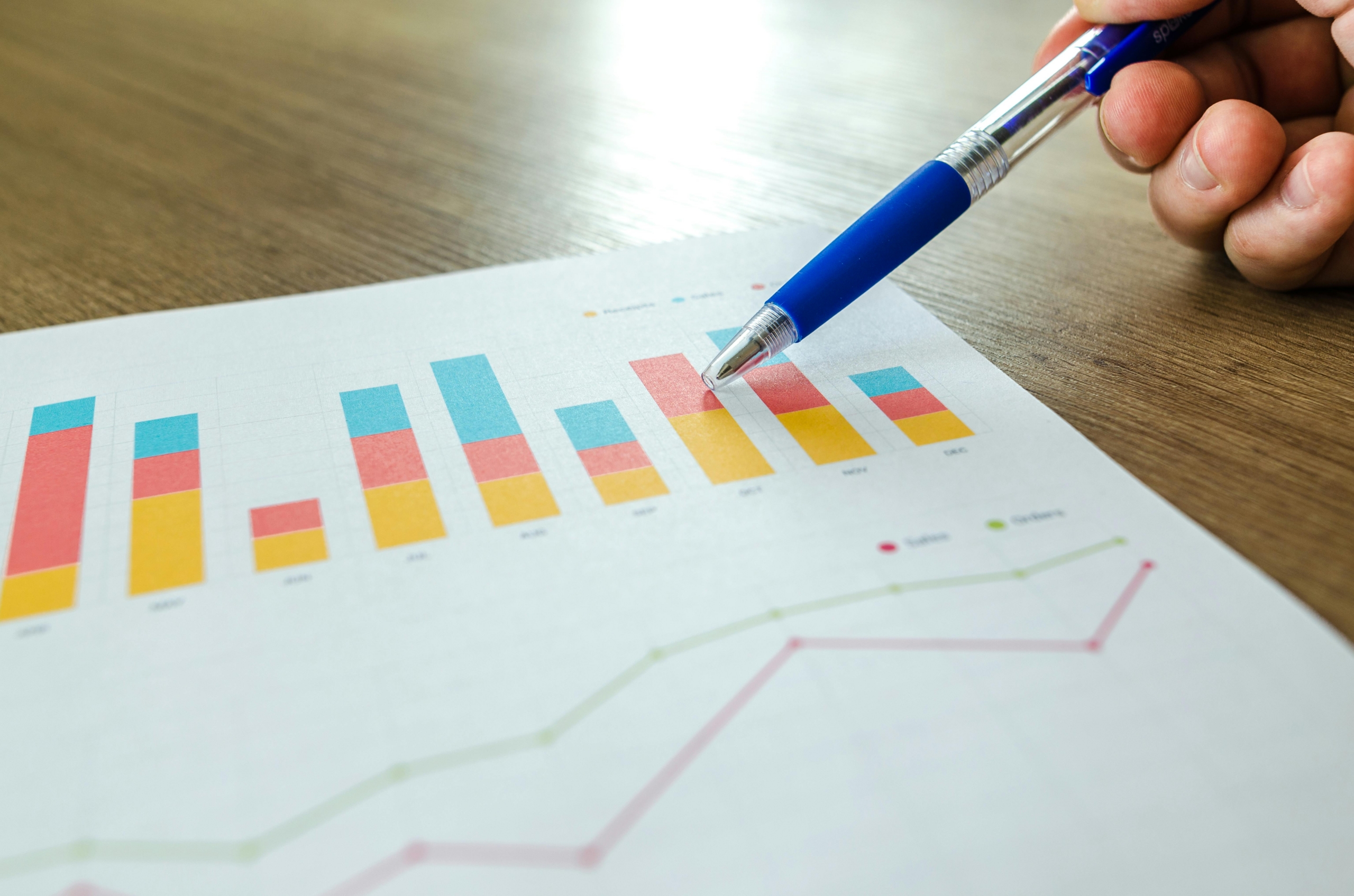 Blue pen pointing at graphs on paper.