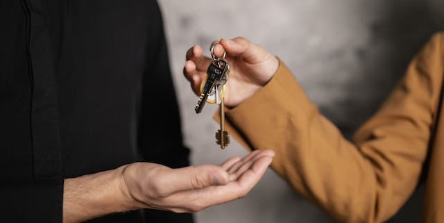 person-handing-over-house-keys-to-another-person person-handing-over-house-keys-to-another-person