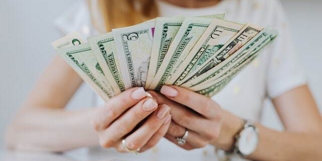 person-holding-rent-dollar-bills-splayed-out-in-their-hands person-holding-rent-dollar-bills-splayed-out-in-their-hands