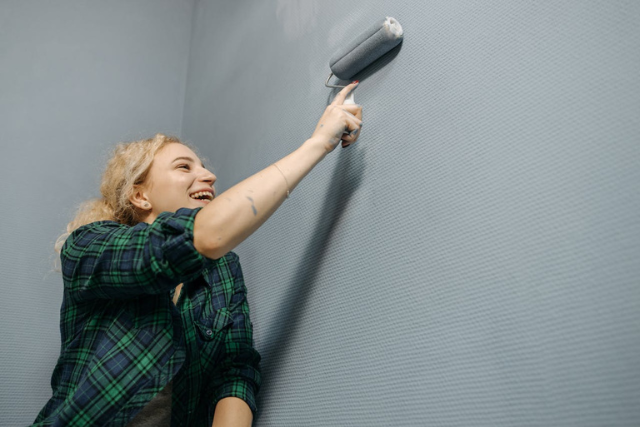 smiling-woman-painting-a-textured-wall-with-a-roller