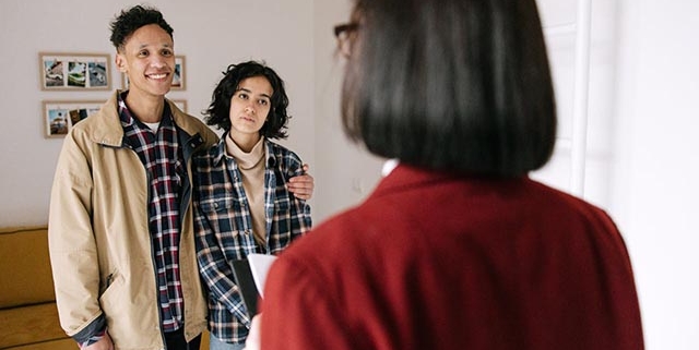 young-couple-speaking-with-a-woman-holding-a-clipboard-inside-a-home young-couple-speaking-with-a-woman-holding-a-clipboard-inside-a-home
